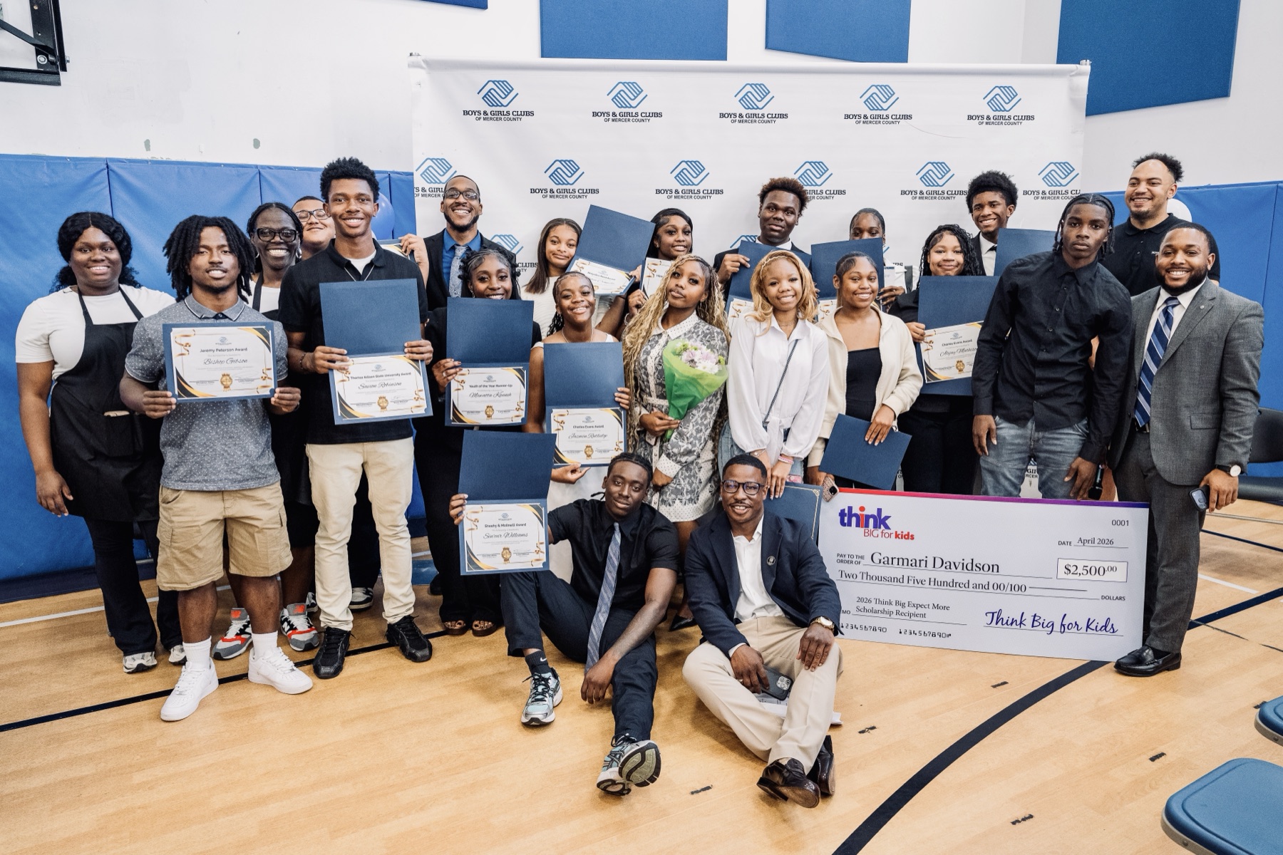 CJ Burnett with a youth cohort holding scholarship awards at a Trenton community event.